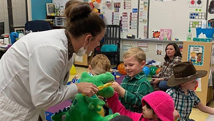 Dentist showing kids how to brush teeth