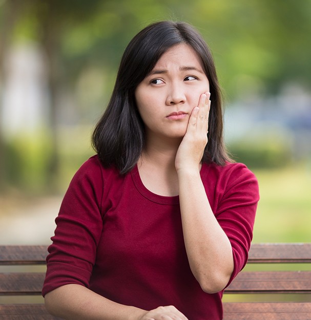 Woman holding jaw outdoors