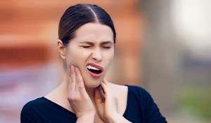 Grimacing woman holding jaw joints