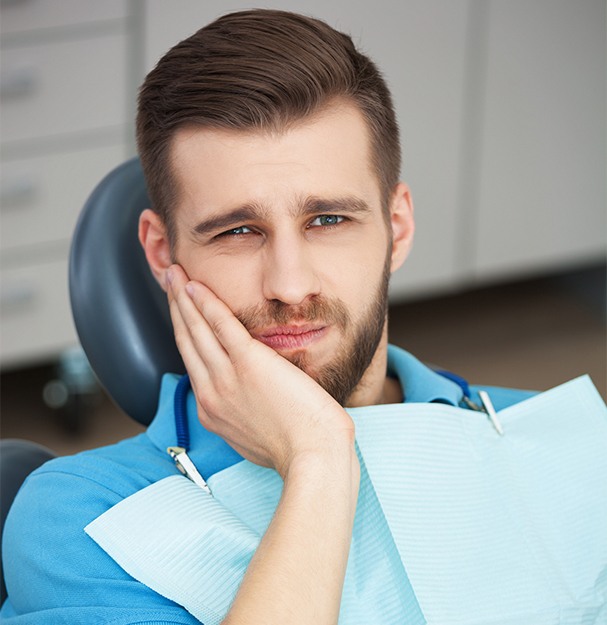 Man in dental chair holding cheek