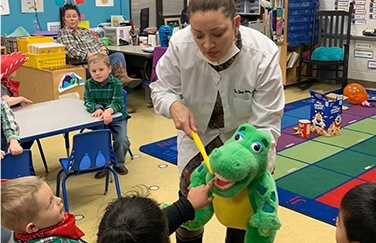 Dentist showing kids how to brush teeth