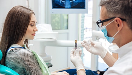 Dentist showing patient a dental implant model