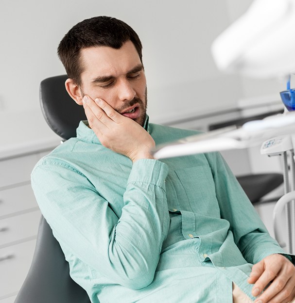 Man in dental chair holding jaw