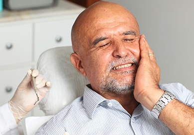 Man in dental chair holding his cheek